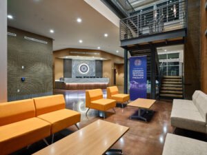Commercial interior photograph of the multi-level ERTF entrance lobby featuring modern orange seating, polished concrete floors, steel staircase, and reception desk by Dwayne Hickson, Graphic Productions in Oak Ridge, TN.