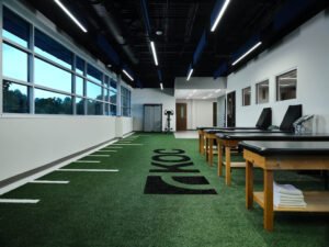 Architectural interior photograph of modern KOC physical therapy clinic featuring indoor turf and treatment tables in Knoxville, TN.