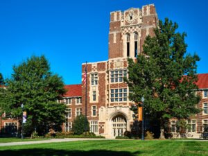 Exterior architectural photograph of Ayres Hall clock tower, stone arch entrance, and green lawn at the University of Tennessee in Knoxville, TN.