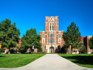 Symmetrical daytime architectural photograph of iconic Ayres Hall brick tower, clock, and green lawn at the University of Tennessee in Knoxville, TN.