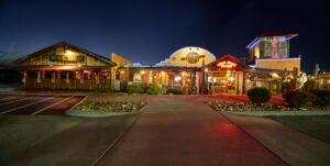 Panoramic commercial exterior night photograph of Iron Boar Saloon and Hogg Shed featuring neon signage and rustic wood siding in Pigeon Forge, TN.