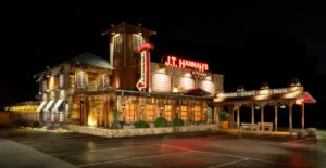 Commercial night architectural photograph of J.T. Hannah's Kitchen exterior with vintage neon signs, rustic wood siding, and brick facade in Pigeon Forge, TN.