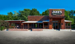 Commercial exterior architectural photograph of Scrambled Jake's Breakfast Co. featuring dark wood siding, timber pergola, and brick patio in Rocky Hill, Knoxville, TN.