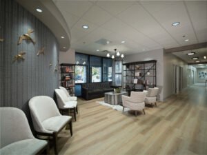 Commercial interior photograph showing a curved feature wall with textured charcoal wallpaper, brass wall art, and open reception seating leading to a corridor by Dwayne Hickson, Graphic Productions in Knoxville, TN.