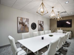 Commercial interior photograph of a modern executive conference room with white leather chairs, brass pendant lighting, and presentation display at Brogan Financial by Dwayne Hickson, Graphic Productions in Knoxville, TN.