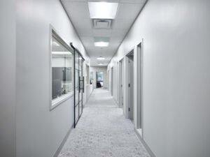 Commercial interior photograph of a modern office hallway featuring patterned carpet tile, sliding glass barn doors with black metal framing, and interior suite windows by Dwayne Hickson, Graphic Productions in Knoxville, TN.