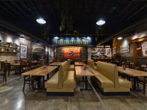 Commercial interior photograph of Buffalo Breakfast Company showing symmetrical leather booths, reclaimed wood dining tables, concrete floors, and rustic wall graphics by Dwayne Hickson, Graphic Productions in Sevierville, TN.