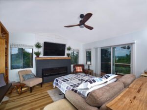 Interior real estate photograph of a modern rustic lake house living room with fold-out sleeper sofa, fireplace, and sliding doors overlooking Douglas Lake by Dwayne Hickson, Graphic Productions in TN.